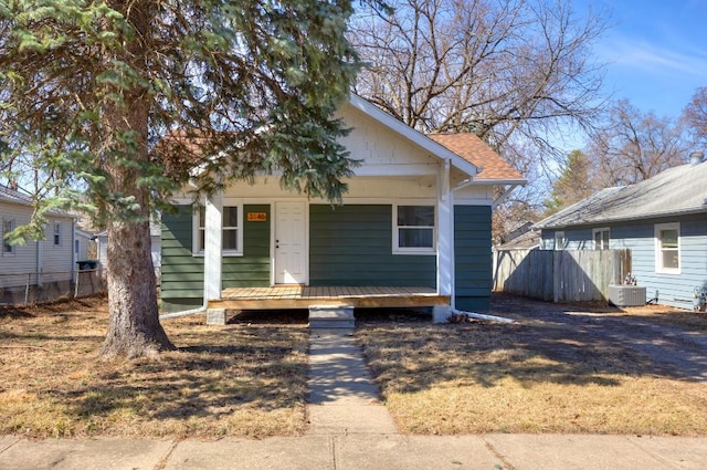 bungalow-style house with a porch, central AC unit, and fence
