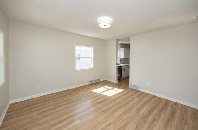 unfurnished room featuring visible vents, light wood finished floors, and baseboards