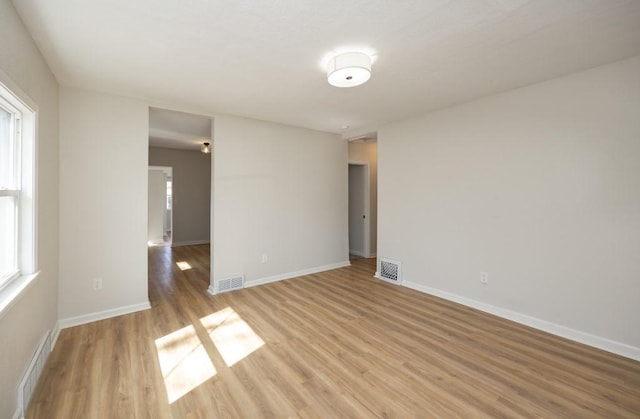 unfurnished room featuring baseboards, visible vents, and light wood-type flooring