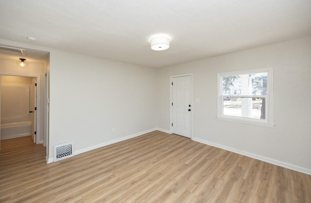 spare room with baseboards, visible vents, and light wood-style floors