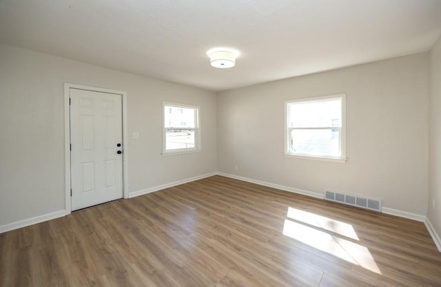 unfurnished room featuring baseboards, visible vents, and wood finished floors
