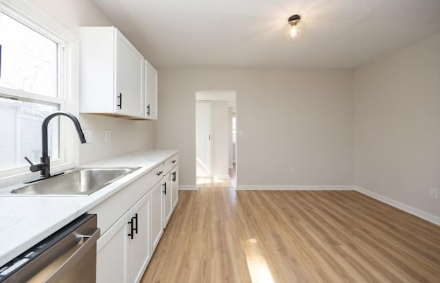 kitchen with light wood-style floors, light countertops, dishwasher, a sink, and white cabinetry