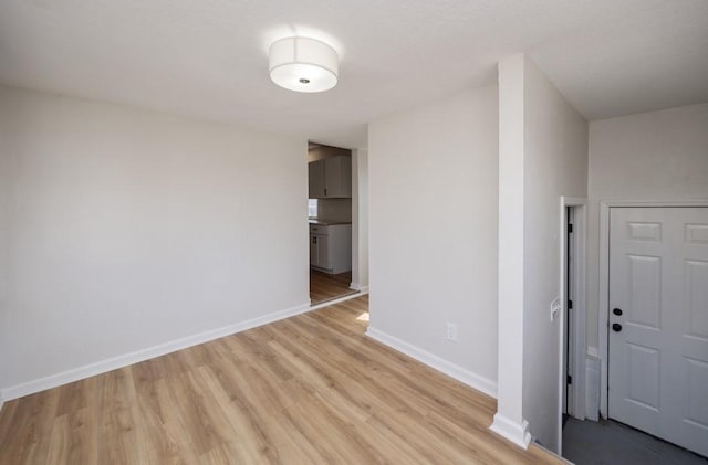 spare room featuring light wood finished floors and baseboards