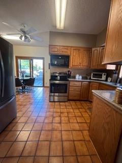 1301 Florida Ave, Ames, IA 50014 - kitchen featuring stainless steel range with electric stovetop, black microwave, freestanding refrigerator, ceiling fan, and brown cabinetry