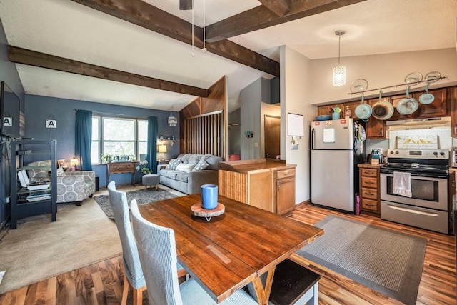 dining room with vaulted ceiling with beams and light wood-style flooring