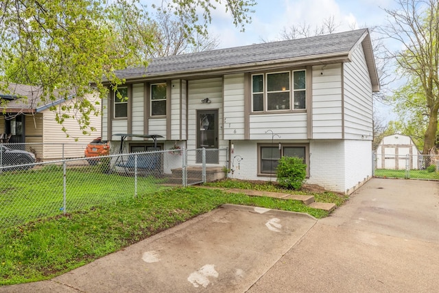 raised ranch featuring a front lawn, an outdoor structure, fence private yard, a storage shed, and brick siding