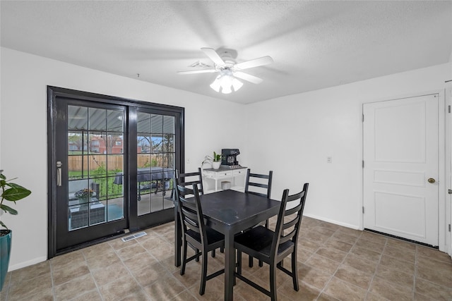 dining space featuring ceiling fan, baseboards, visible vents, a textured ceiling, and light tile patterned flooring