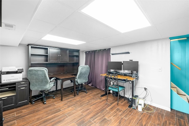 office area with a paneled ceiling, visible vents, and wood finished floors