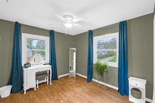 interior space featuring baseboards, a ceiling fan, light wood finished floors, and plenty of natural light