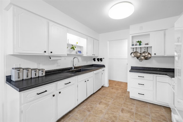 kitchen with dark countertops, open shelves, white cabinets, and a sink