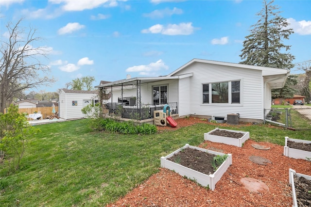 back of property featuring fence, a vegetable garden, and a shed