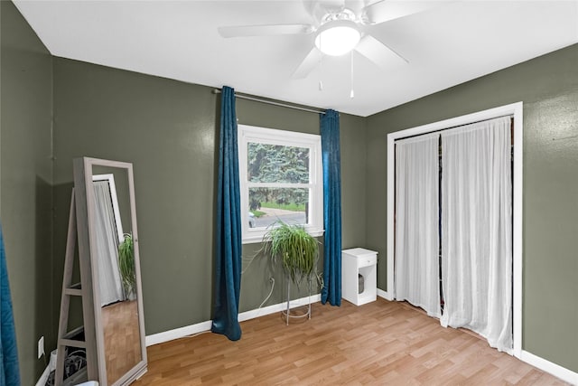 unfurnished bedroom featuring baseboards, light wood-type flooring, a ceiling fan, and a closet