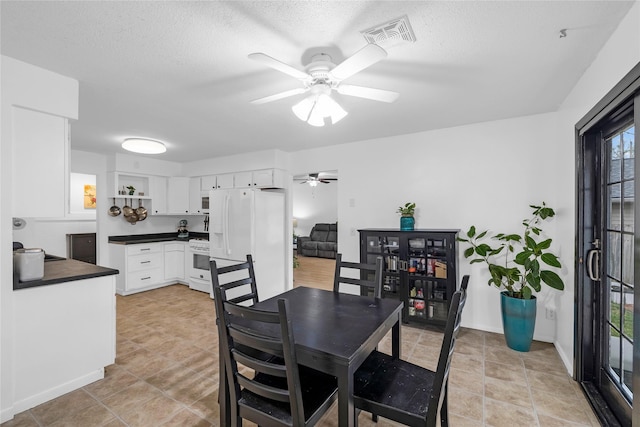 dining space featuring baseboards, visible vents, ceiling fan, and a textured ceiling