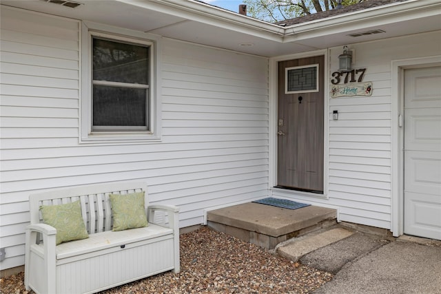 doorway to property with a garage and visible vents