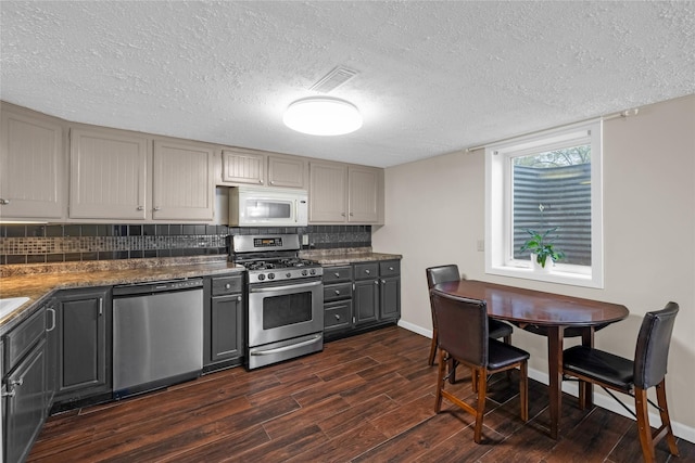 kitchen with gray cabinets, tasteful backsplash, appliances with stainless steel finishes, visible vents, and dark wood-type flooring