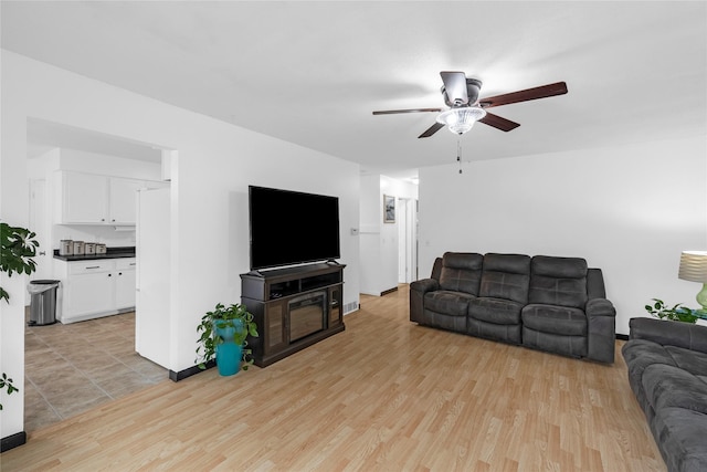 living area with baseboards, light wood-type flooring, and ceiling fan
