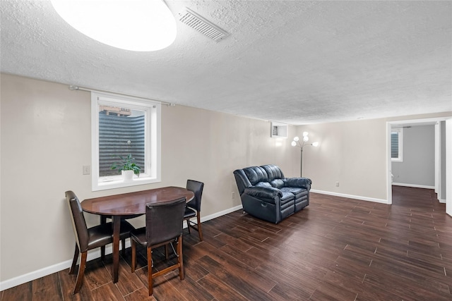 dining room featuring a textured ceiling, visible vents, wood finished floors, and baseboards