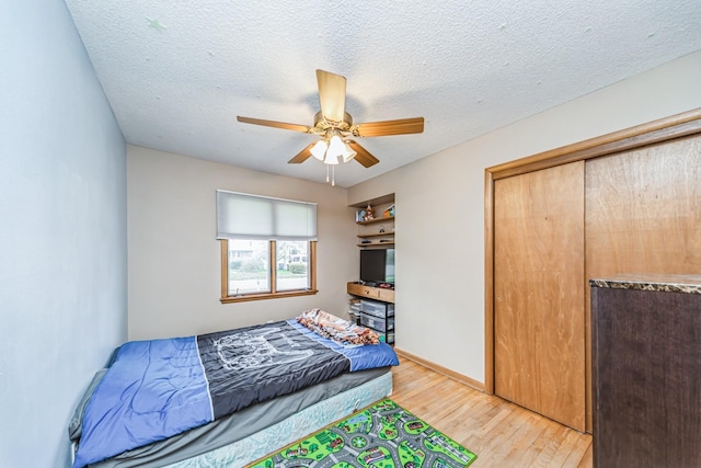 bedroom with a textured ceiling, ceiling fan, light wood finished floors, and a closet