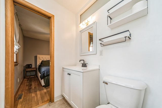 bathroom featuring toilet, visible vents, wood finished floors, and vanity
