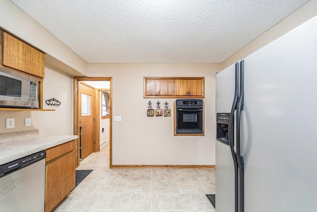 kitchen featuring brown cabinetry, a textured ceiling, stainless steel appliances, and light countertops