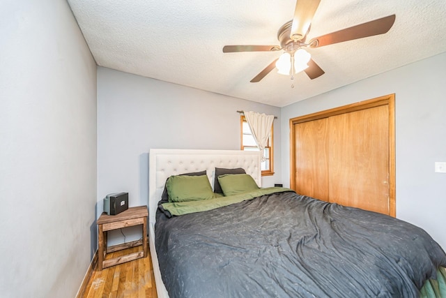 bedroom featuring a closet, a ceiling fan, baseboards, a textured ceiling, and wood finished floors