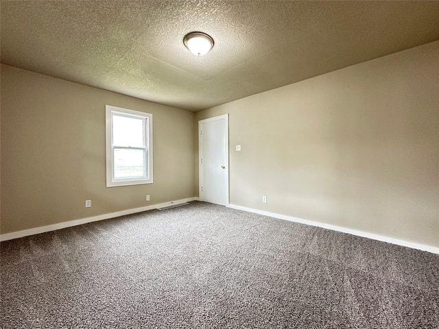 empty room with carpet, a textured ceiling, and baseboards