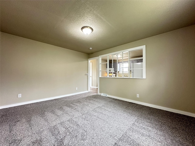 carpeted empty room with a textured ceiling, visible vents, and baseboards