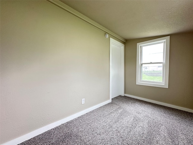 carpeted spare room with a textured ceiling and baseboards