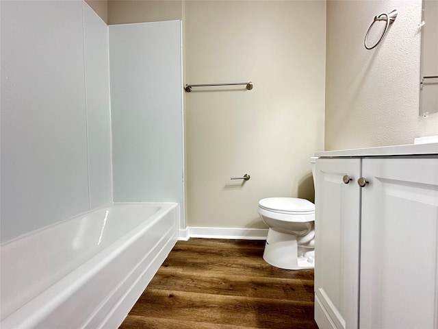 bathroom with toilet, vanity, wood finished floors, and baseboards