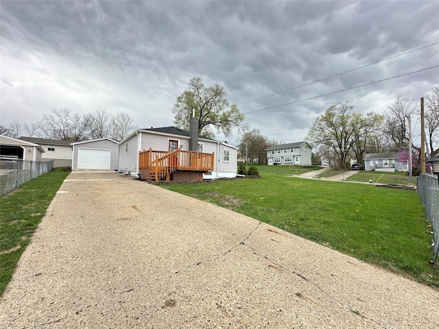 view of front of home featuring driveway, a wooden deck, an outbuilding, fence, and a front lawn