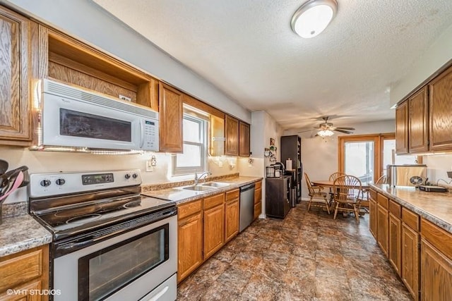 kitchen with a sink, stone finish floor, stainless steel appliances, and plenty of natural light