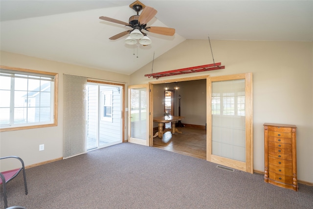 spare room with lofted ceiling, carpet flooring, visible vents, baseboards, and a ceiling fan