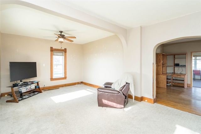 unfurnished room featuring arched walkways, carpet flooring, a ceiling fan, and baseboards