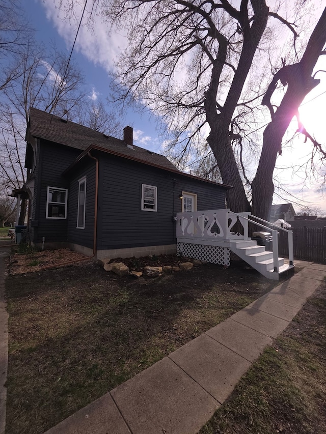 view of side of property with a wooden deck, fence, and a chimney