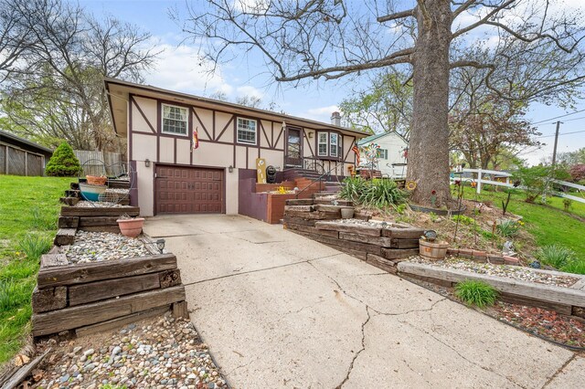 view of front of house with stucco siding, fence, a front yard, concrete driveway, and an attached garage