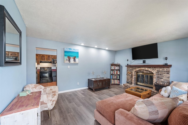 living area featuring recessed lighting, a brick fireplace, baseboards, a textured ceiling, and wood finished floors