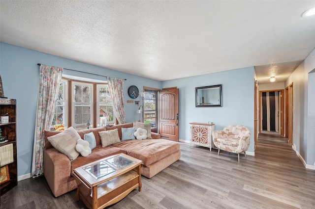 living room featuring a textured ceiling, wood finished floors, and baseboards