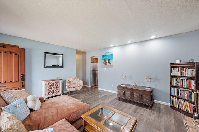 living area with recessed lighting, a textured ceiling, wood finished floors, and baseboards