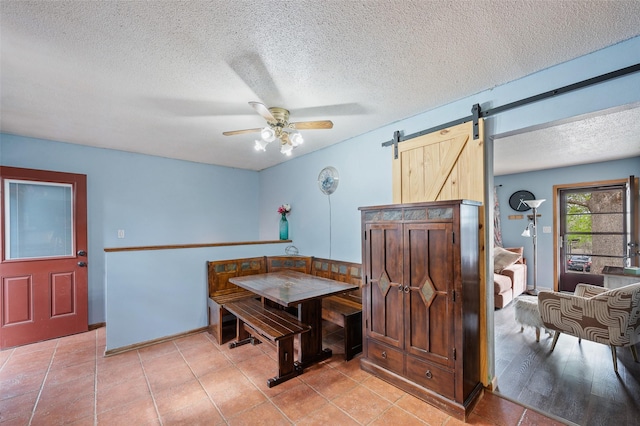 dining space with a textured ceiling, a barn door, and ceiling fan