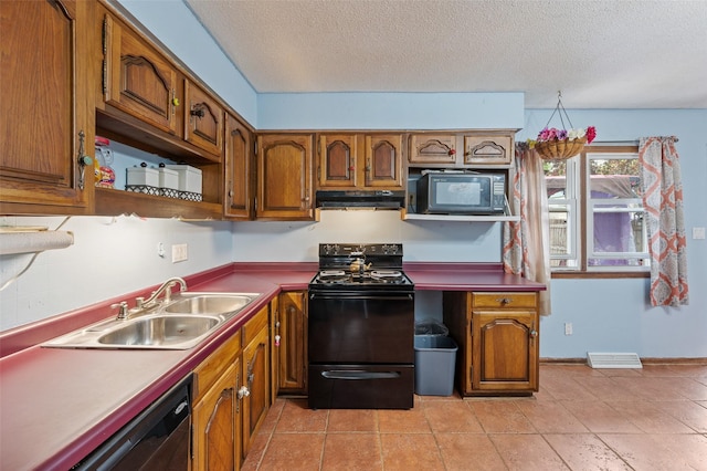 kitchen featuring brown cabinetry, under cabinet range hood, black appliances, a sink, and a textured ceiling