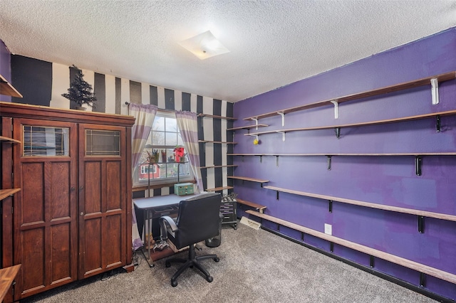 carpeted home office featuring wallpapered walls and a textured ceiling