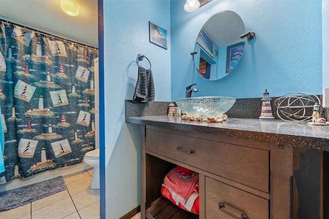 full bath featuring tile patterned flooring, toilet, a textured wall, vanity, and curtained shower