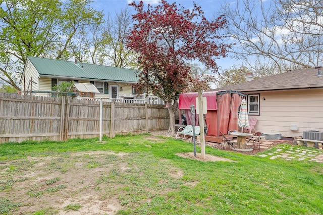 view of yard featuring central AC and fence
