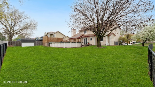 view of yard with an outdoor structure, a storage shed, a fenced in pool, and a fenced backyard