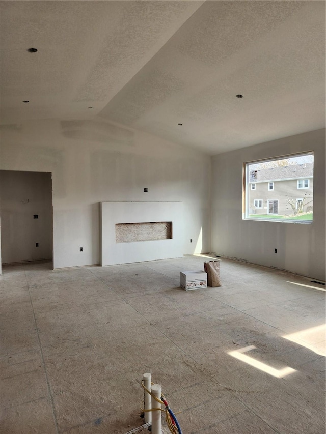 unfurnished living room featuring a textured ceiling and lofted ceiling