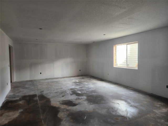 spare room with a textured ceiling and concrete flooring