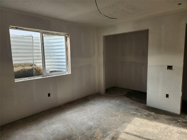 spare room with unfinished concrete floors and a textured ceiling