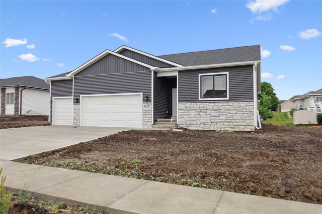 2323 N 8th Ave E, Newton, IA 50208 - view of front facade featuring stone siding, a garage, driveway, and roof with shingles