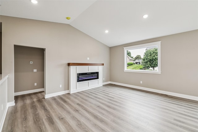 2323 N 8th Ave E, Newton, IA 50208 - unfurnished living room with lofted ceiling, light wood finished floors, a glass covered fireplace, and recessed lighting