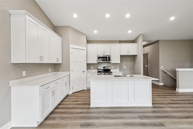 2323 N 8th Ave E, Newton, IA 50208 - kitchen with stainless steel appliances, light wood-style flooring, white cabinets, a kitchen island with sink, and recessed lighting